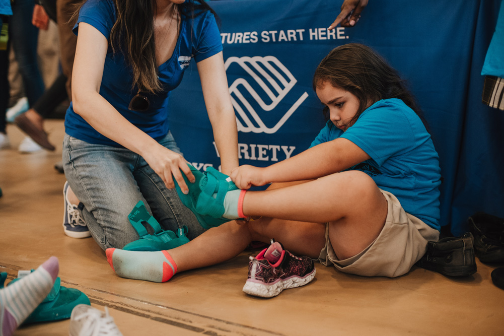 An LA Variety Boys and Girls Club member tries on So iLL climbing shoes for the first time.